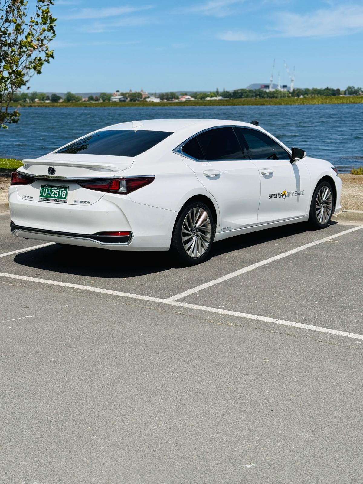 White Lexus ES300h luxury taxi by the lake